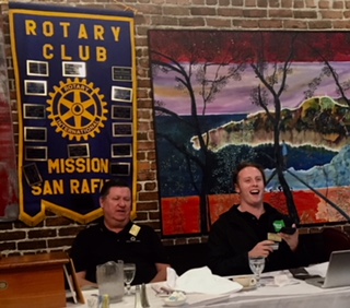 Rotary Club banner with members in meeting 